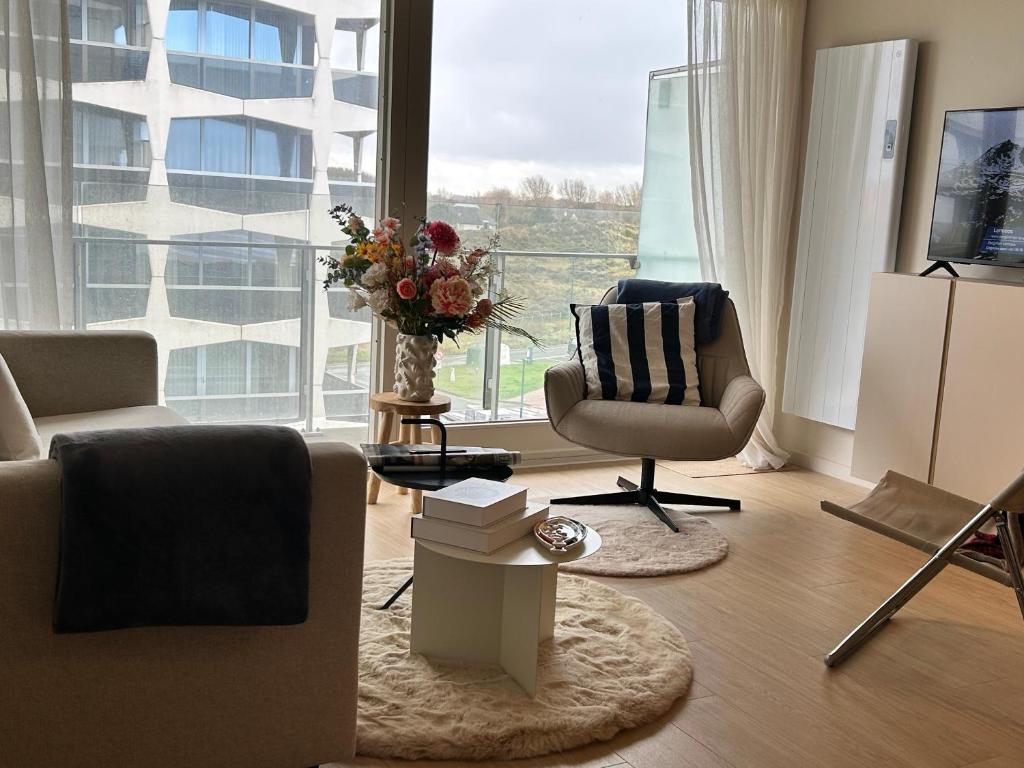 un salon avec un canapé et une chaise et une grande fenêtre dans l'établissement Windekind402, à La Panne