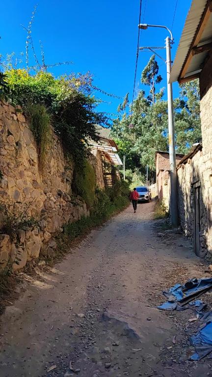 a person walking down a dirt road next to a building at Wonderful Full House in Ollantaytambo