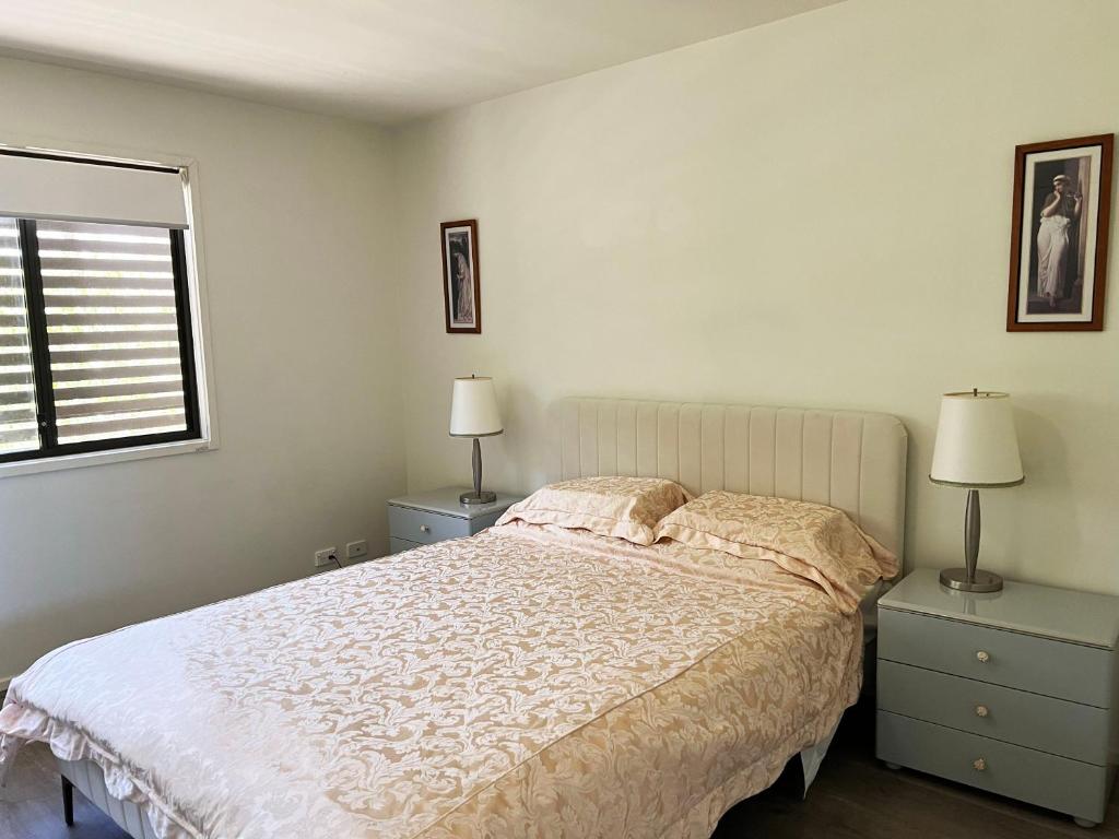 Un dormitorio blanco con una cama y dos mesitas de noche. en Spacious Family Townhouse near Kingston & Manuka, en Fyshwick
