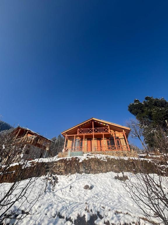 a building on top of a snow covered mountain at Baserah - Stay & Cafe in Jibhi