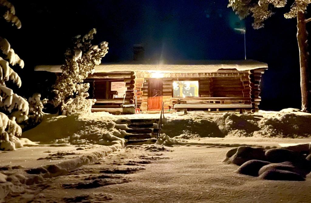 a log cabin in the snow at night at Suvantokoto Riverside Log Cabin in Rovaniemi