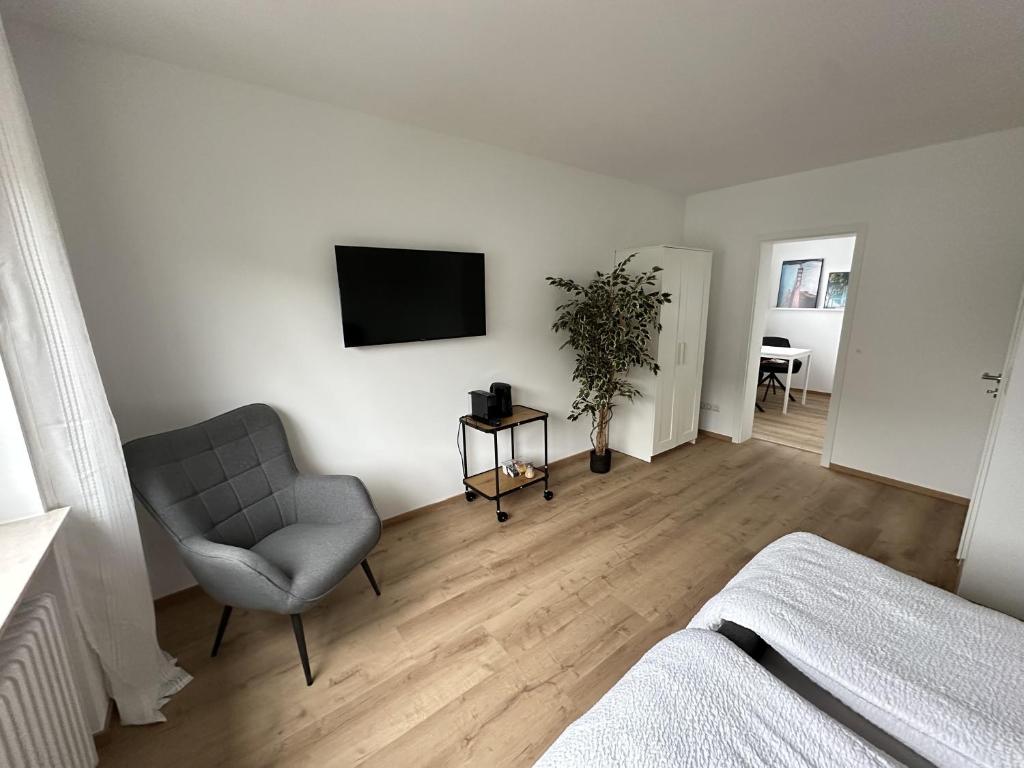 um quarto branco com uma cadeira e uma televisão na parede em Modernes 2-Zimmer Apartment in Aschaffenburg em Aschaffenburg