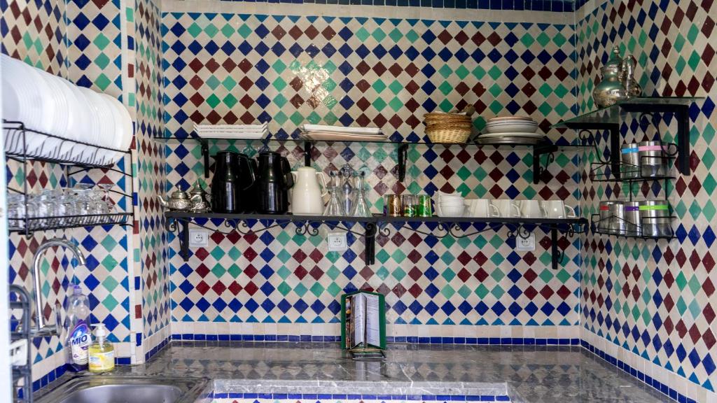 eine Küche mit einem Waschbecken und einer gefliesten Wand in der Unterkunft Riad Green House in Fès