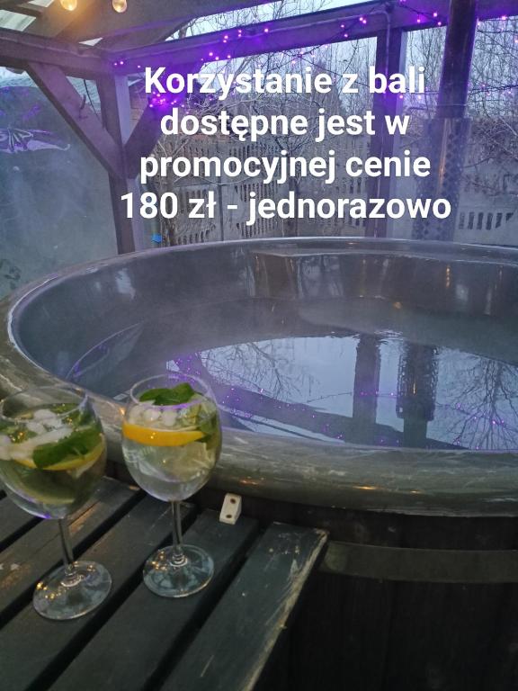 two wine glasses sitting on a table next to a tub at Anna in Czarny Młyn