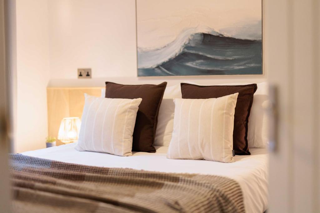 a bedroom with a bed with pillows and a painting at Secluded Sanctuary On The River in Christchurch