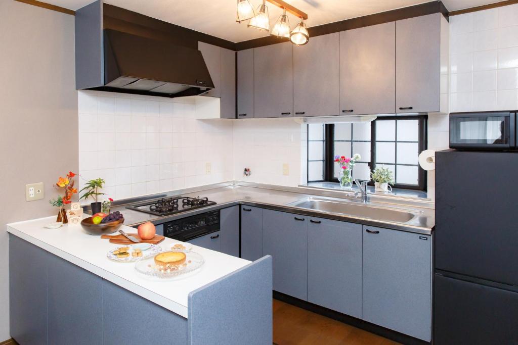 eine Küche mit grauen Schränken und einer weißen Arbeitsplatte in der Unterkunft 一棟貸 風kaze in Ōgaki