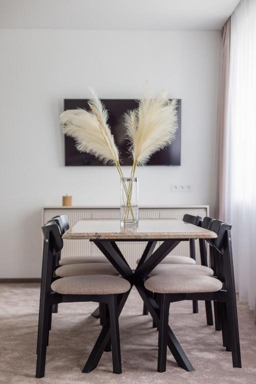 a dining room table with chairs and a vase with feathers at Varenastay in Varėna