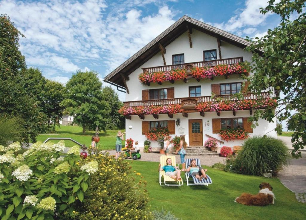 eine Gruppe von Menschen, die vor einem Haus auf Gartenstühlen sitzen in der Unterkunft Wofahanslhof in Eschlkam