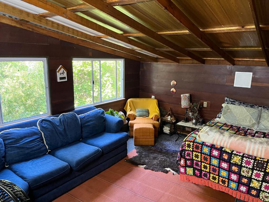 a living room with a blue couch and a bed at Choupana das Araucárias in Sapiranga