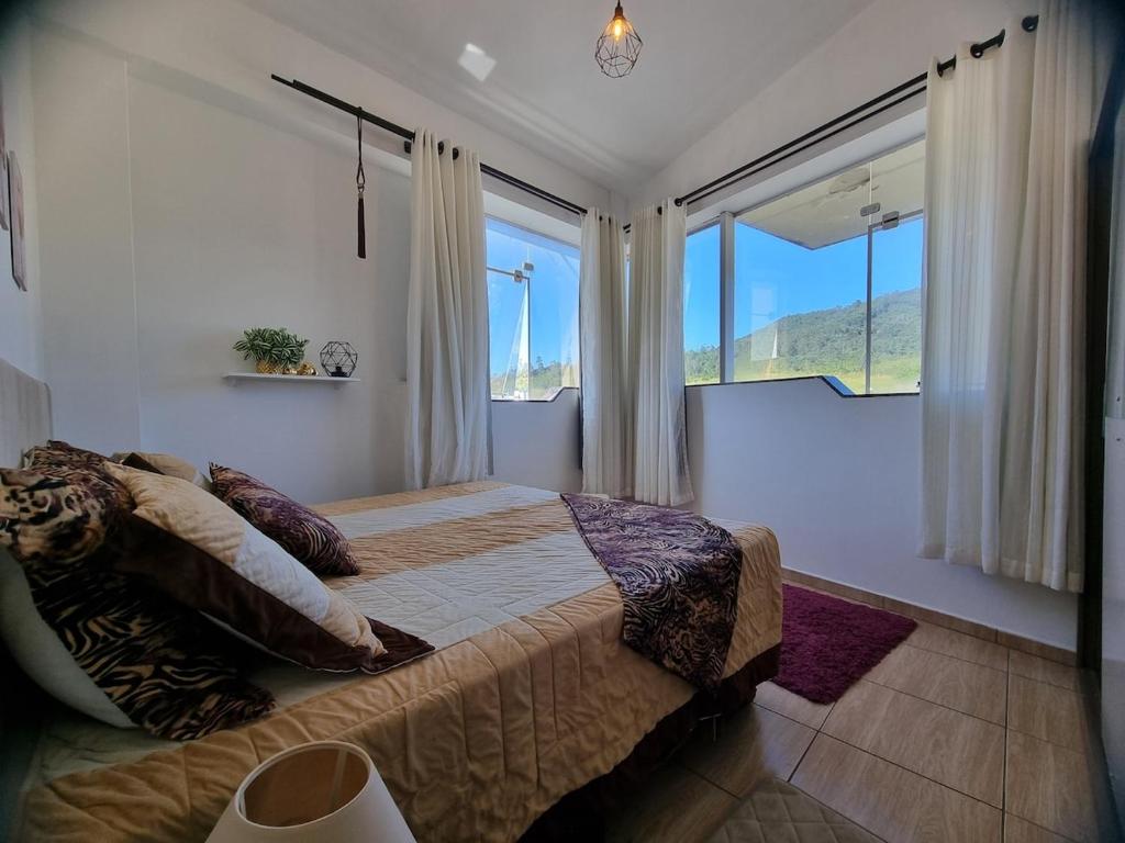 Un dormitorio con una cama grande en una habitación con ventanas. en Ape da Deisi Termas, en Gravatal