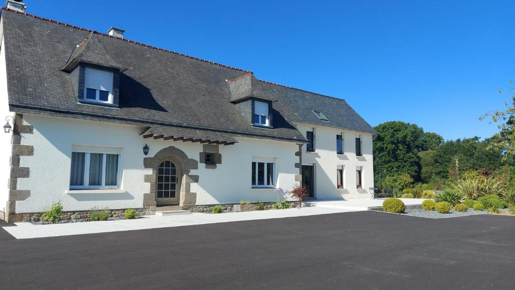 a white house with a black roof and a driveway at Maison de Luciné in Combourg