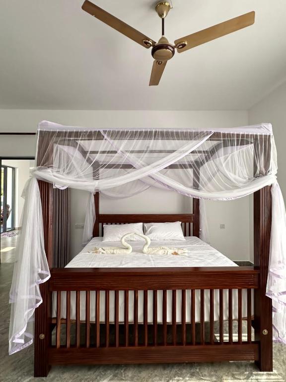 a bedroom with a canopy bed with a ceiling fan at LiIi Villa Sri Lanka in Aluthgama