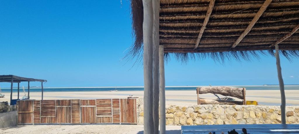 a beach with a straw umbrella and the ocean at Giraffe House Vilankulo in Vilanculos