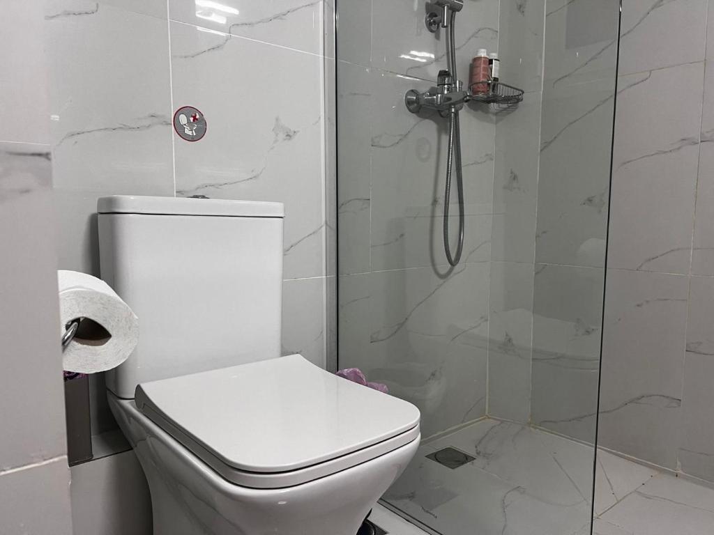 a white bathroom with a toilet and a shower at Ithakis Rooms in Athens