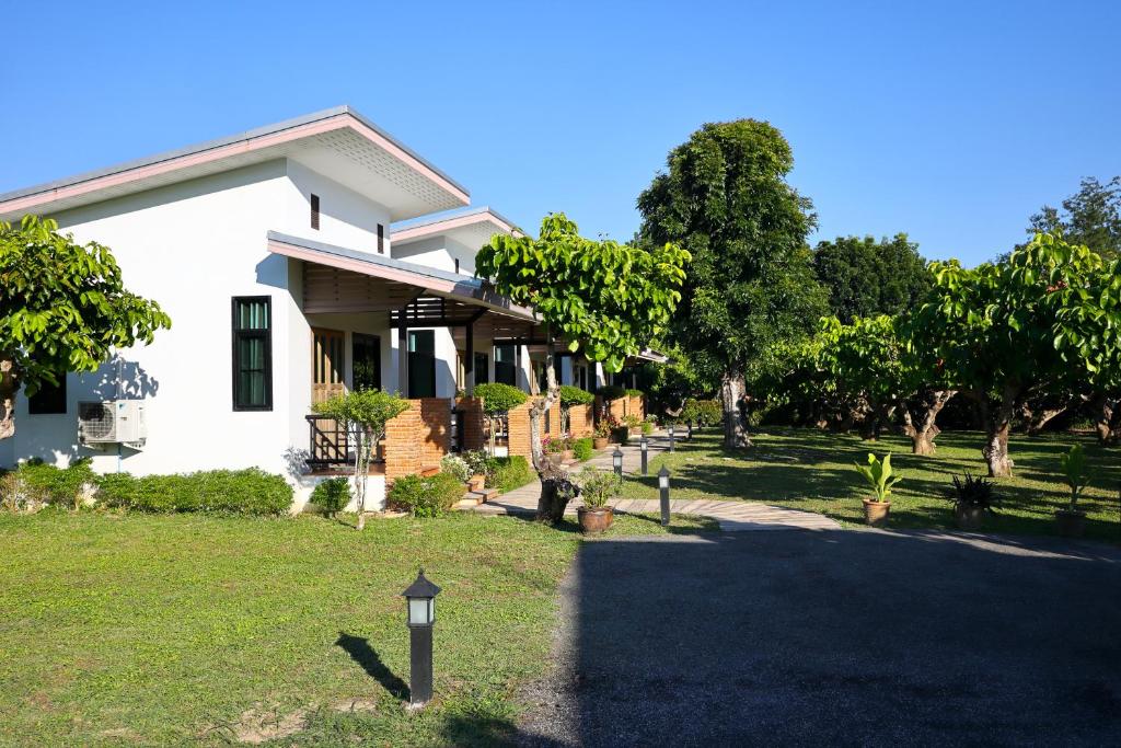 a white house with a yard with trees at Chiang Mai Garden Bungalows in Chiang Mai