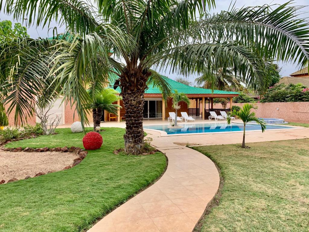 a palm tree in a yard next to a swimming pool at L'Anse des Amarantes in Saly Portudal