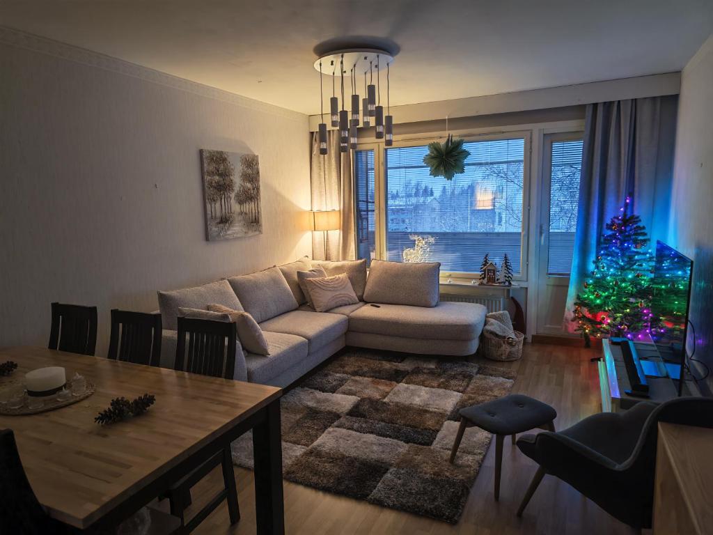 a living room with a couch and a christmas tree at Tievastreet Harmony Apartment in Rovaniemi