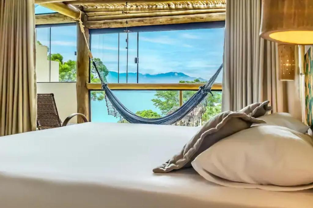 a bed with a hammock in a room with a window at OPN Guest House Ilhabela in Ilhabela