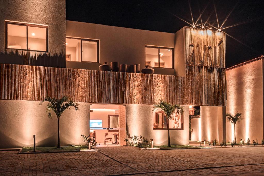 a building with palm trees in front of it at night at Pousada Aysú in Japaratinga
