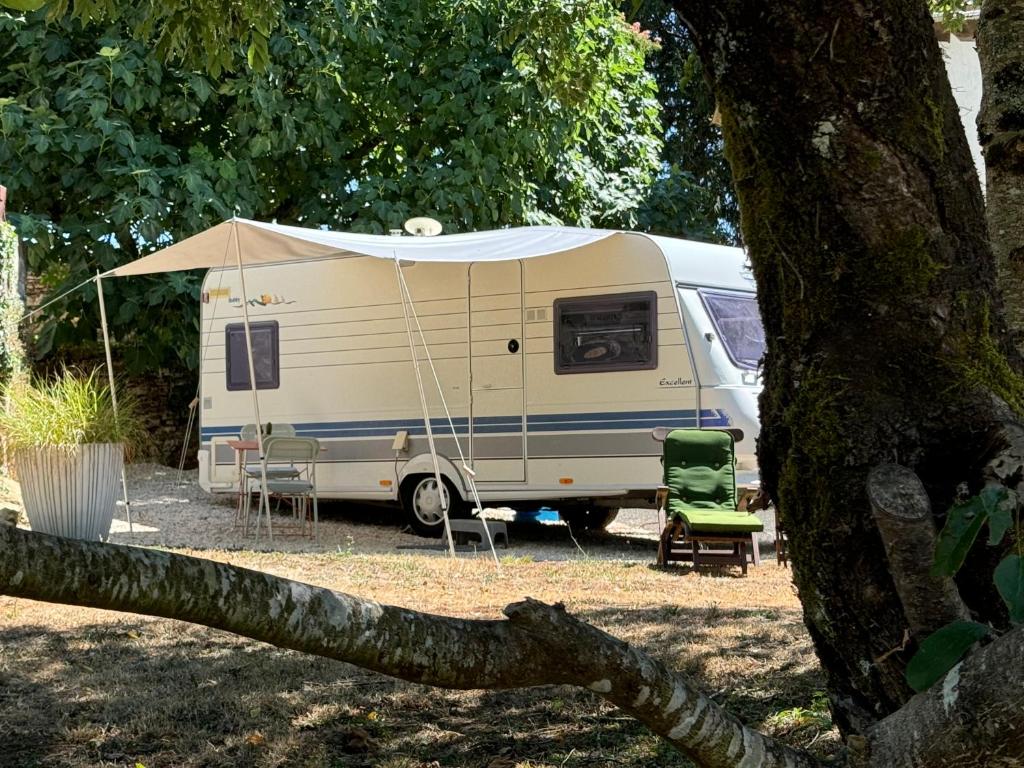 una caravana blanca con una tienda de campaña y una silla en Luxe caravan met rust, ruimte en uitzicht, en Saint-Sulpice-dʼExcideuil