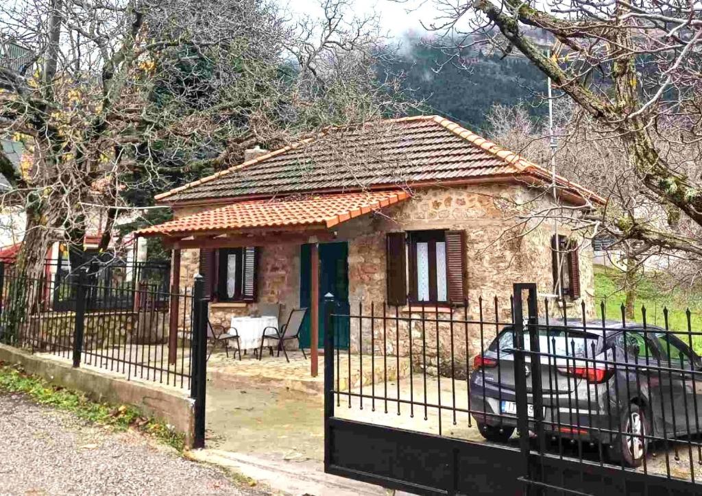 uma pequena casa atrás de uma cerca com um carro na frente em Vrachni Stone House em Ano Zachlorou