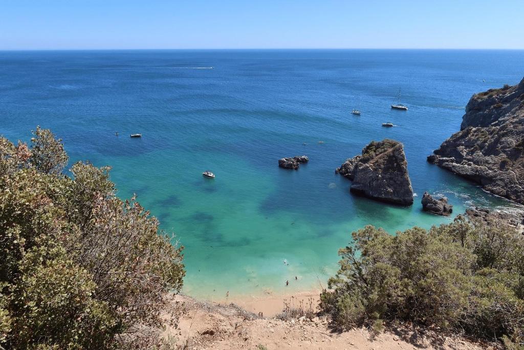 une vue d'une plage avec des bateaux dans l'eau dans l'établissement Just Sezimbra- Modern Apt 3 Min from Beach, à Sesimbra
