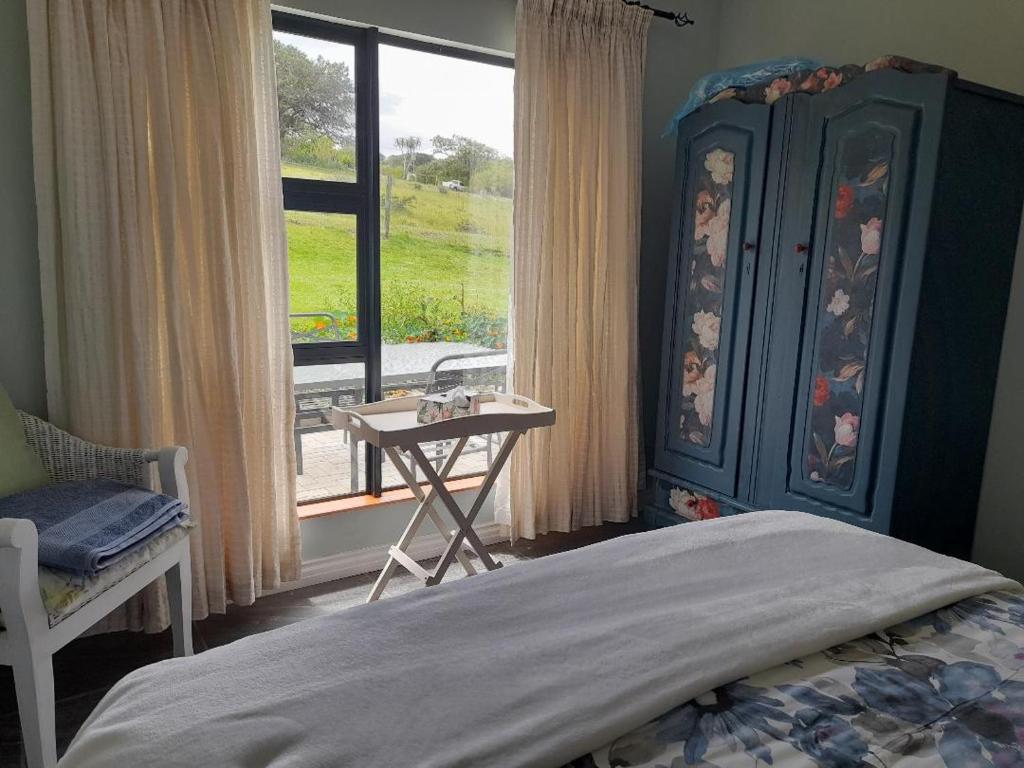 a bedroom with a bed and a table and a window at Zebra Crossing in Bushmans River Village