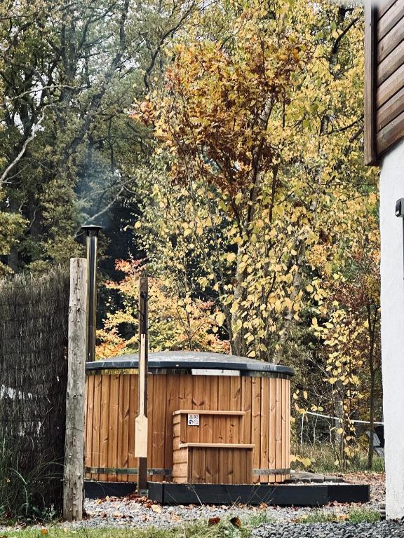 a wooden shed in a yard next to a fence at La Clairiere - Erezee- 3 bedroom chalet in Érezée