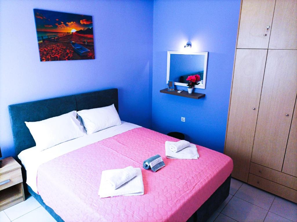 een blauwe slaapkamer met een bed met een roze sprei bij OINO APARTMENT in Corfu-stad