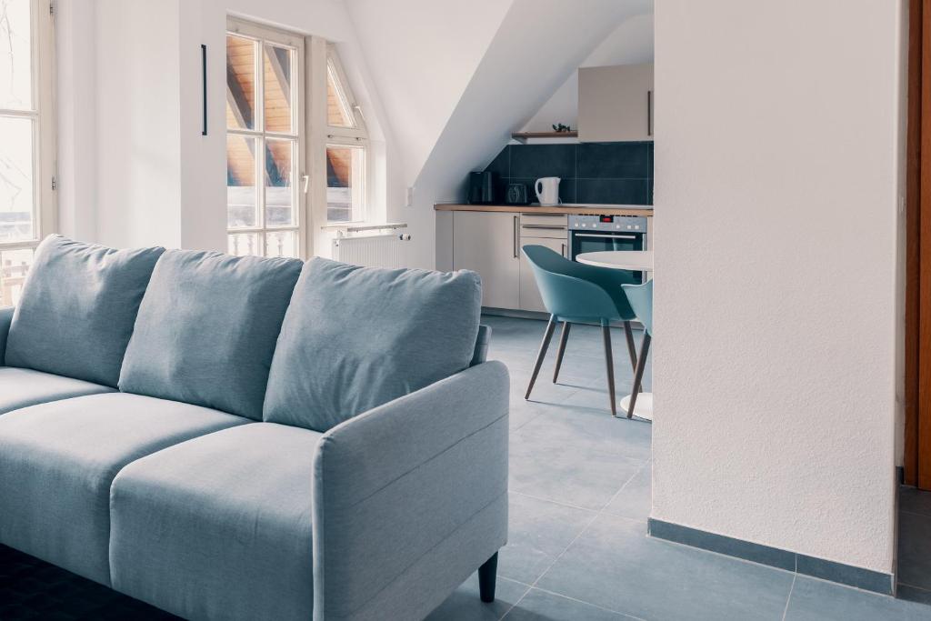 Una sala de estar con un sofá azul y una cocina. en Moderne 2 Zimmer Wohnung im Herzen von Karlsruhe 64m2 2 OG, en Karlsruhe