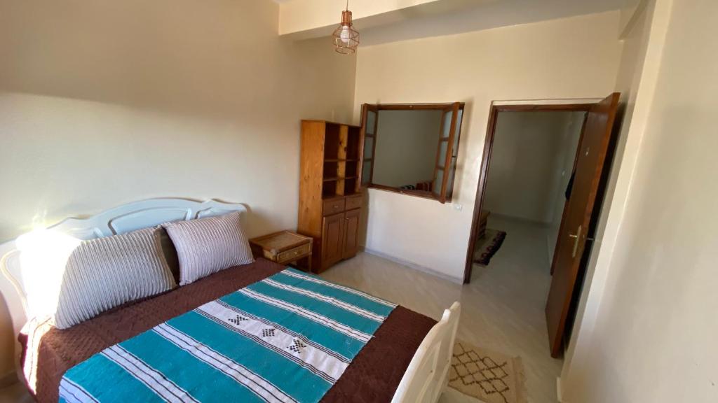 1 dormitorio con cama y espejo. en Gypsy Surf Maroc Hostel, en Tamraght Ouzdar
