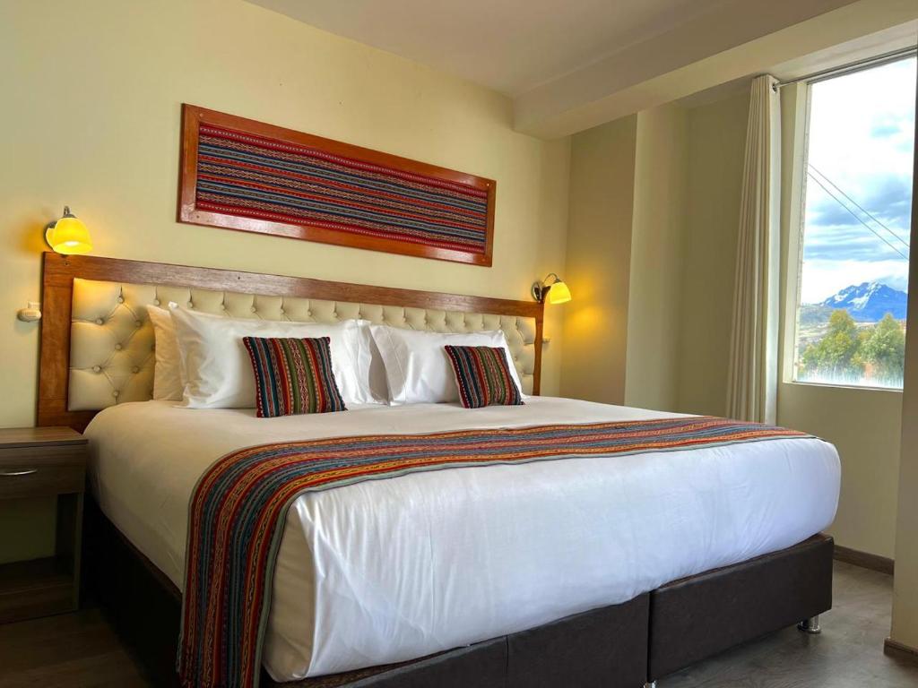 a bedroom with a large white bed with a window at Hotel Chinchero Boutique & Tours in Chinchero