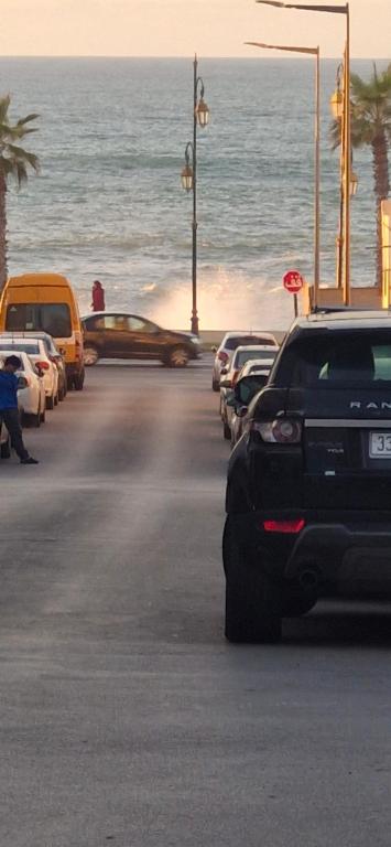 a group of cars parked on a street next to the ocean at Appartement Océan in Rabat