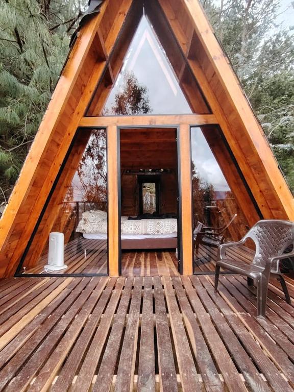 a cabin with a large window on a wooden deck at Refugios de Altaguita in Suesca