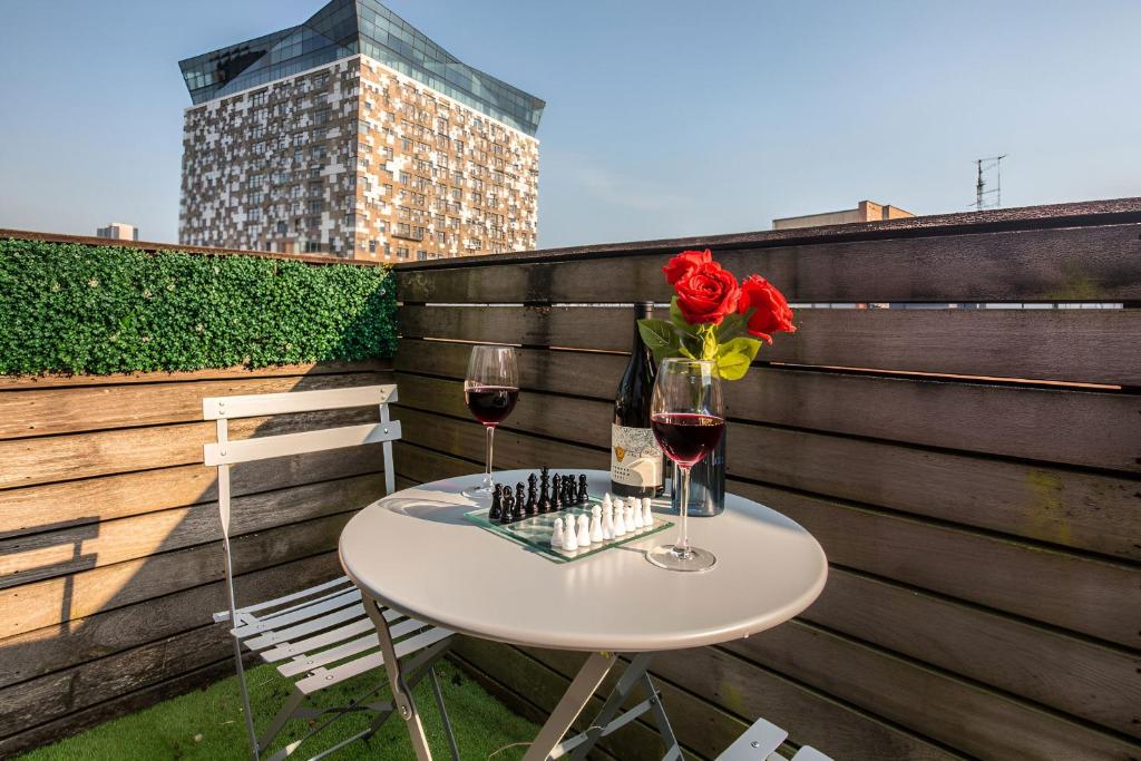 a table with a vase of flowers and two glasses of wine at City Centre 2BR2BA Balcony Apt@The CubeMailbox in Birmingham