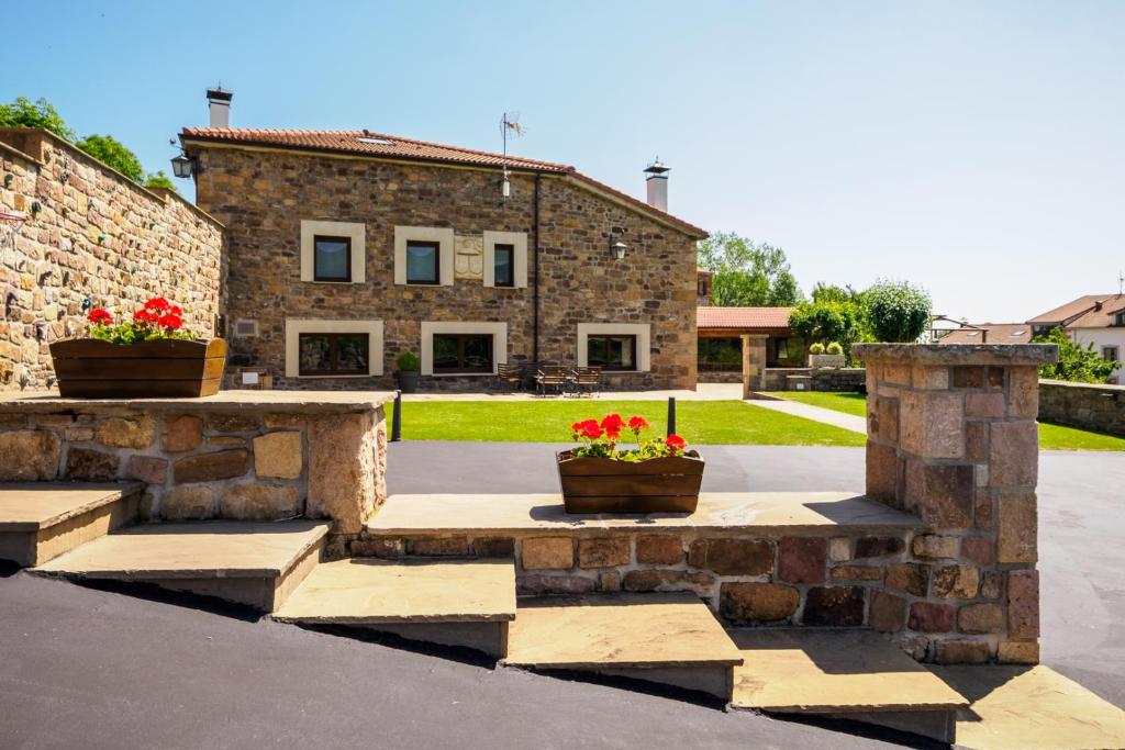 a stone building with two potted flowers in front of it at La Casa De Los Pedros in Villar