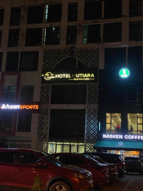 a building with a hotel unitaria sign and cars parked outside at Mekla Hotel Studio Apartment in Gua Musang