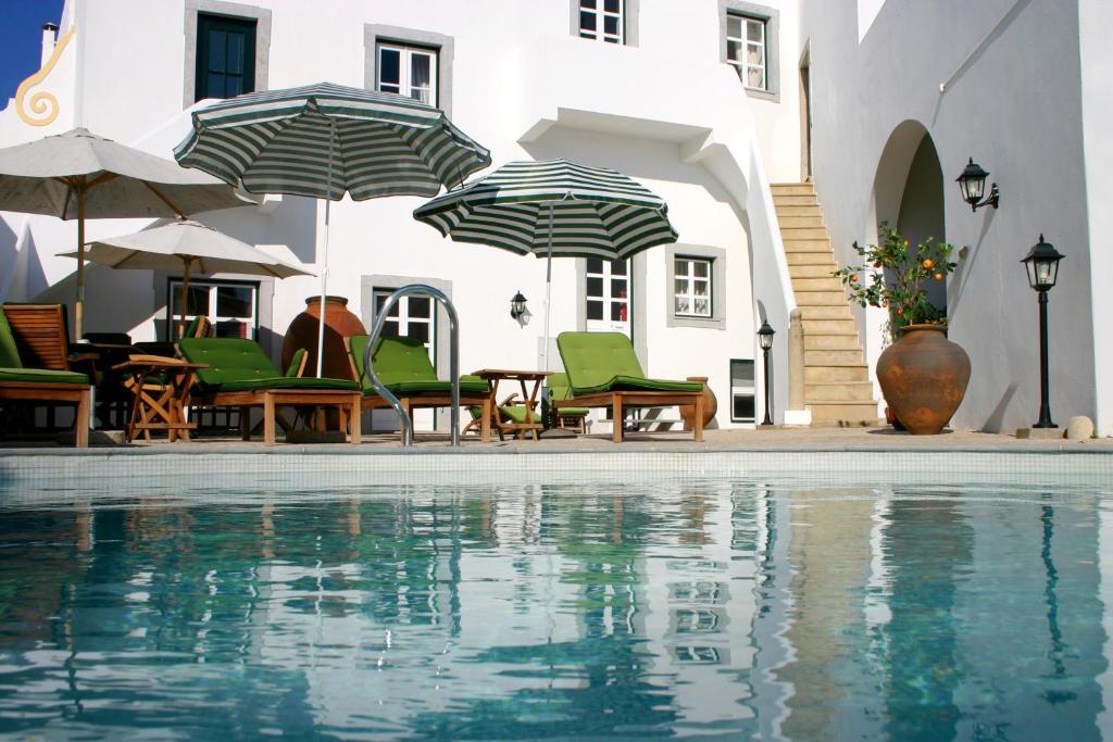 una piscina con sillas y sombrillas junto a un edificio en Casa de Estoi, en Estói