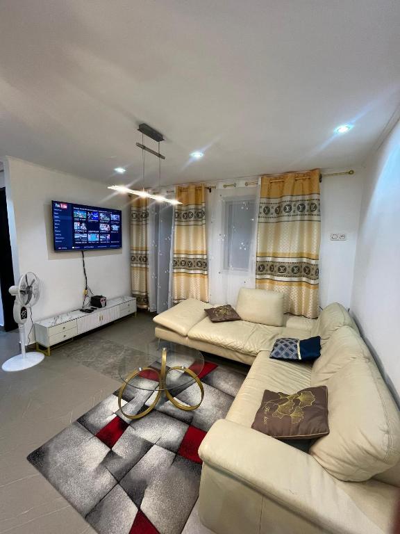 a living room with two couches and a flat screen tv at Studio Meublé Bonamoussadi 4è in Bonamoussadi