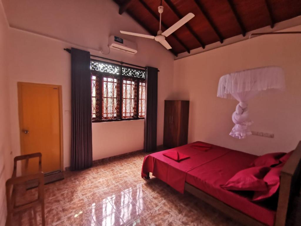 Un dormitorio con una cama roja y una gran ventana. en Green Relax Villa, en Mirissa