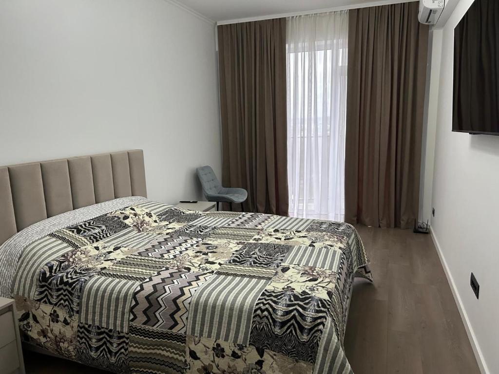 Un dormitorio con una cama y una silla y una ventana. en Apartment in centrul orasului, en Chişinău