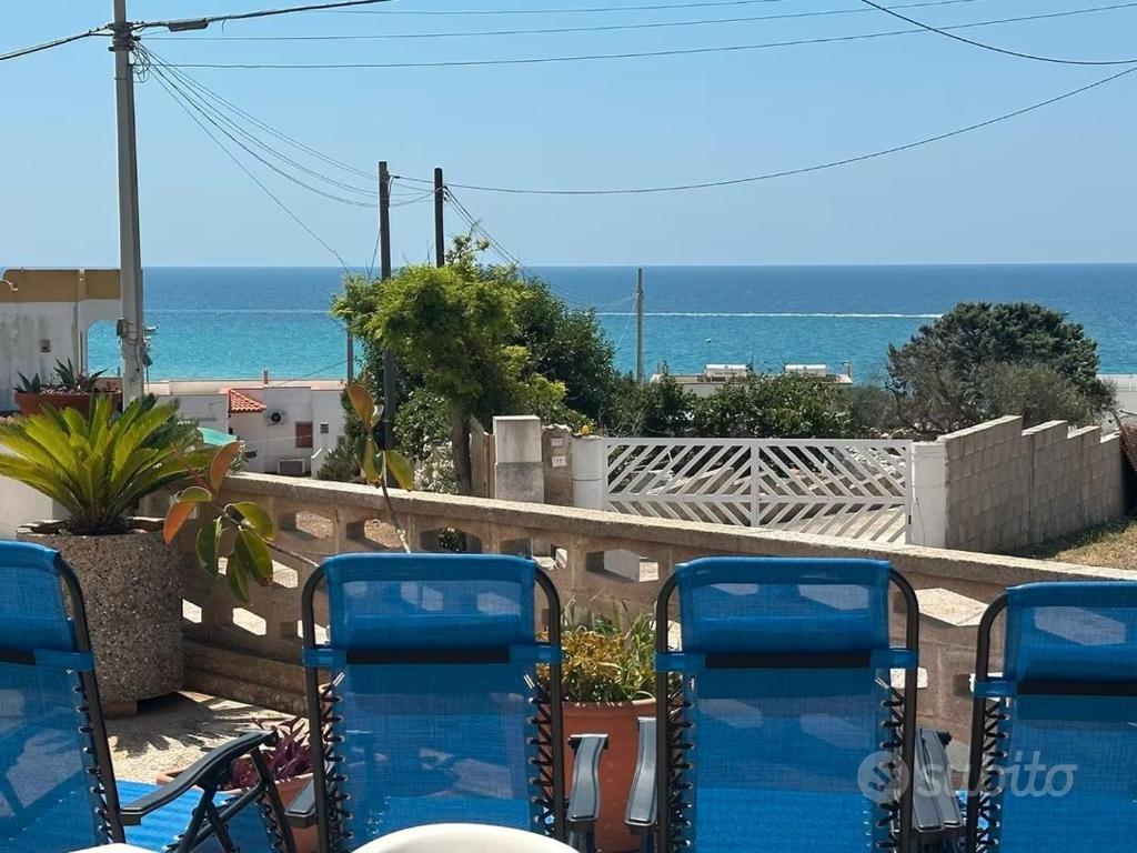 een groep blauwe stoelen op een balkon met uitzicht op de oceaan bij Villetta Mirion in Marina San Gregorio