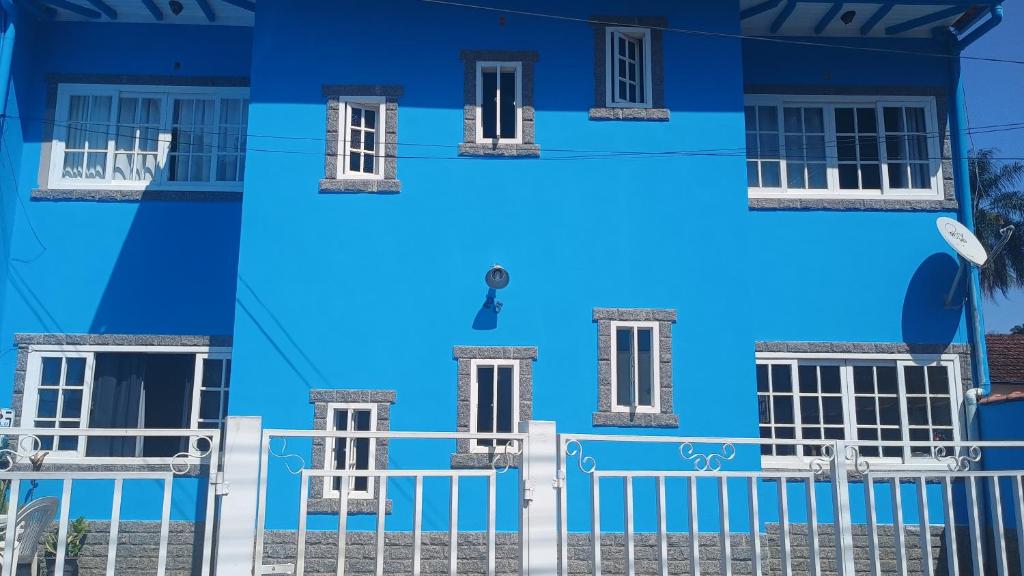 a blue house with a white fence in front of it at Apartamento para até 8 pessoas em Conservatória in Conservatória