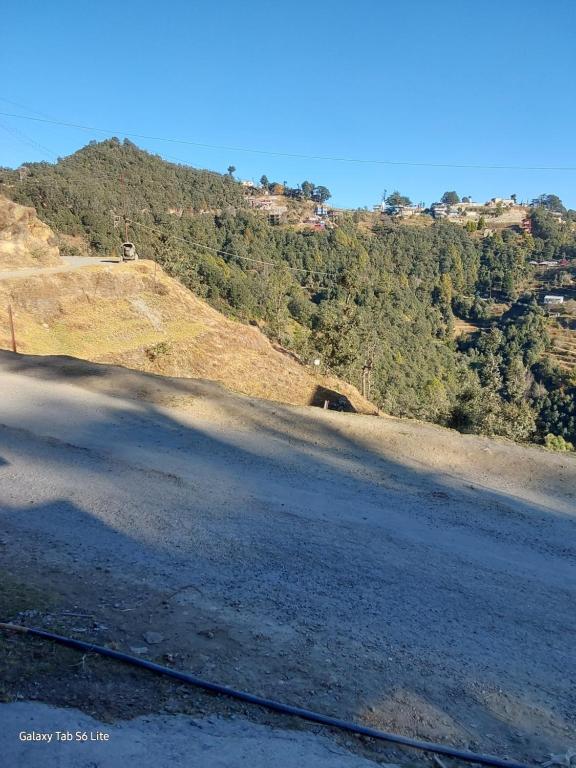 an empty road next to a hill with trees at COMMANDER VILLa in Mukteswar
