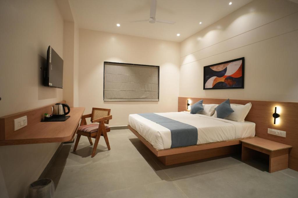 ein Schlafzimmer mit Bett, Schreibtisch und Fernseher in der Unterkunft Kolas Grand - Hotel and Convention Center in Warangal