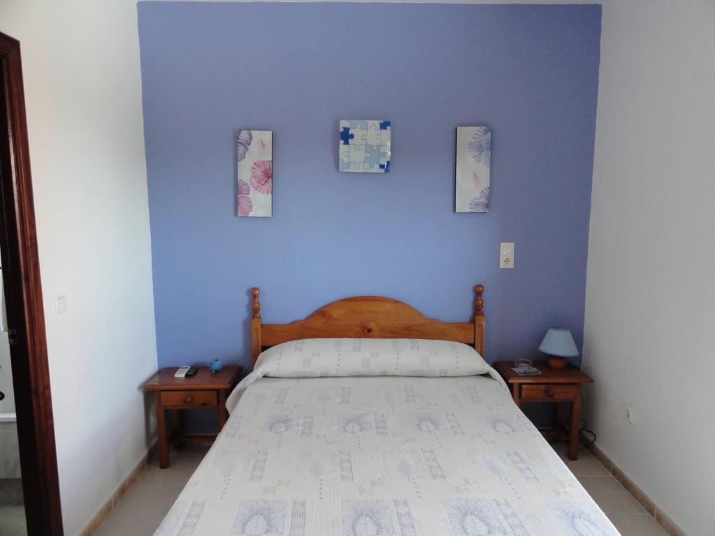 Hostal la Campa في شيكلانا دي لا فرونتيرا: غرفة نوم زرقاء مع سرير وطاولتين ليليتين
