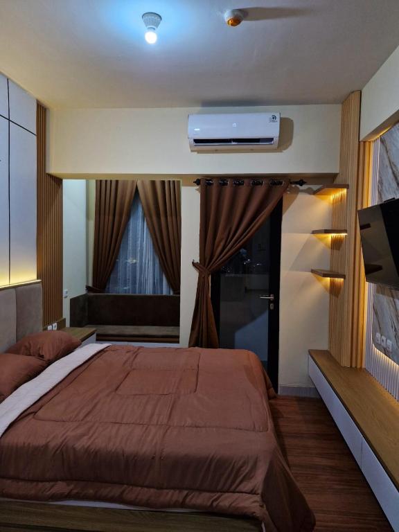 a bedroom with a bed and a tv on the wall at Alton City Loft in Jatingaleh