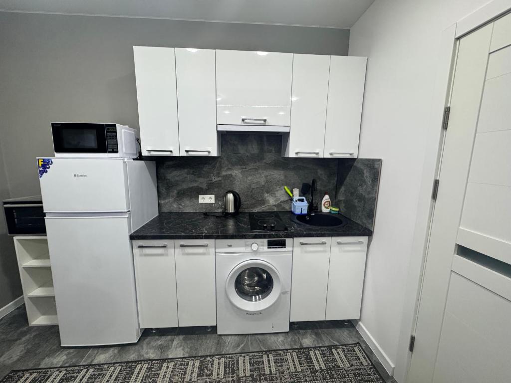 a white kitchen with a washing machine and a sink at Apartament ultra-central in Edineţ