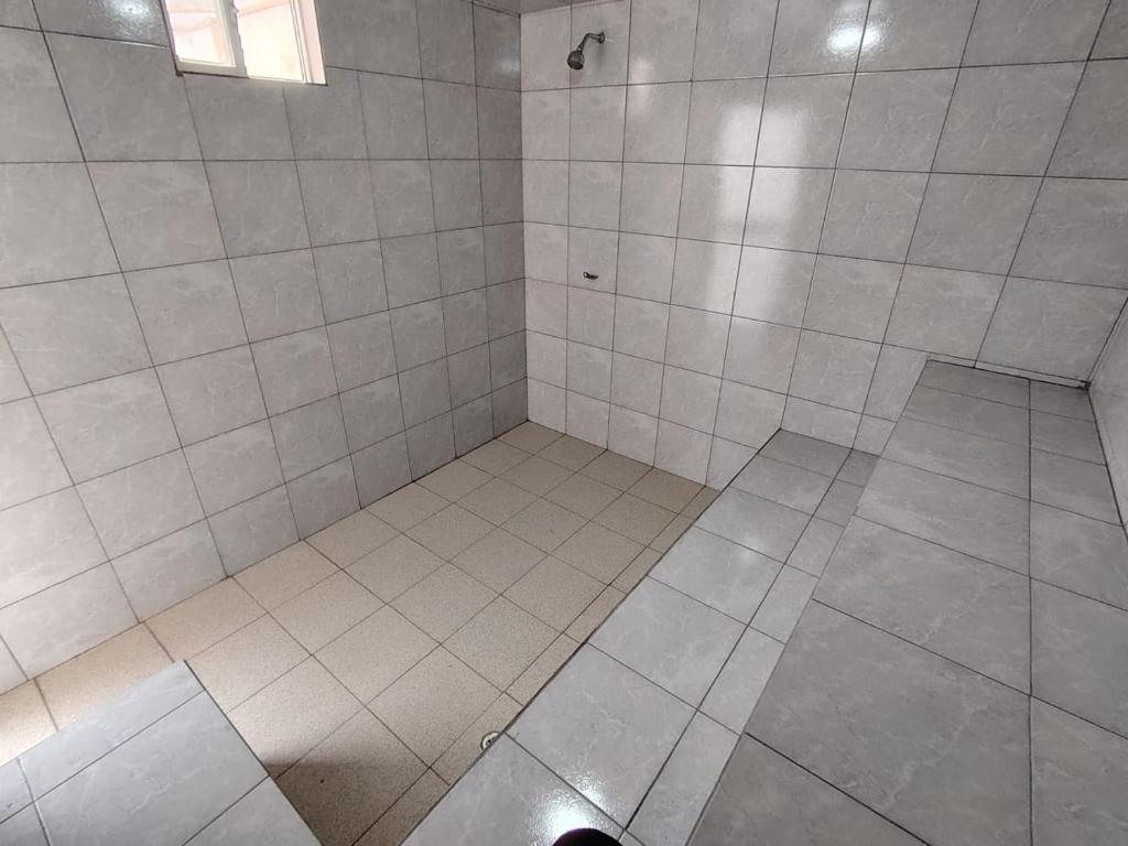 Una ducha de azulejos blancos con un agujero en el suelo. en Coney Camping, en Ambato