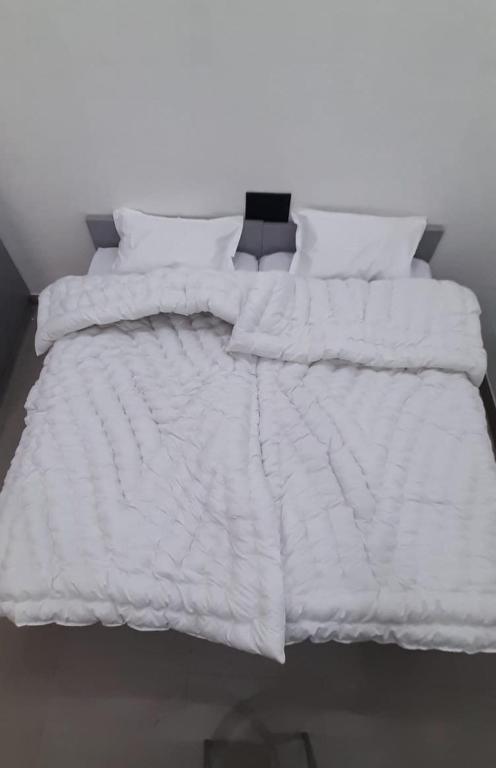 Saran Homestay في آغْرا: سرير مع لحاف ووسائد بيضاء